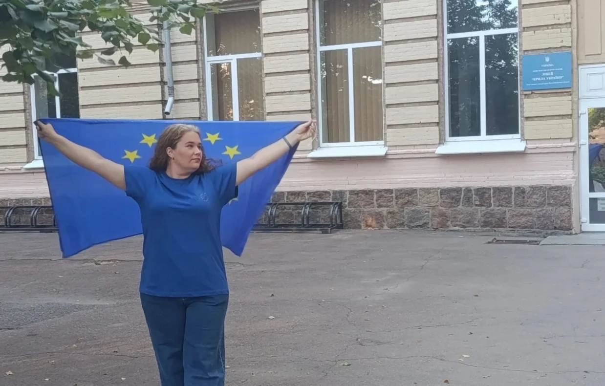Ольга Борзенко біля ліцею "Крила України" з прапором ЄС