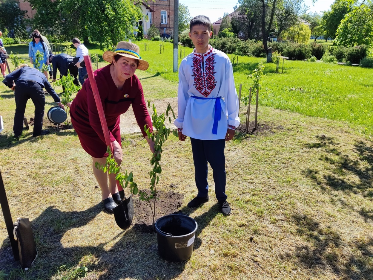 Мама загиблго воїна Віктора Голого - Олена Голікова та учень Дмитрівської філії саджають деревце