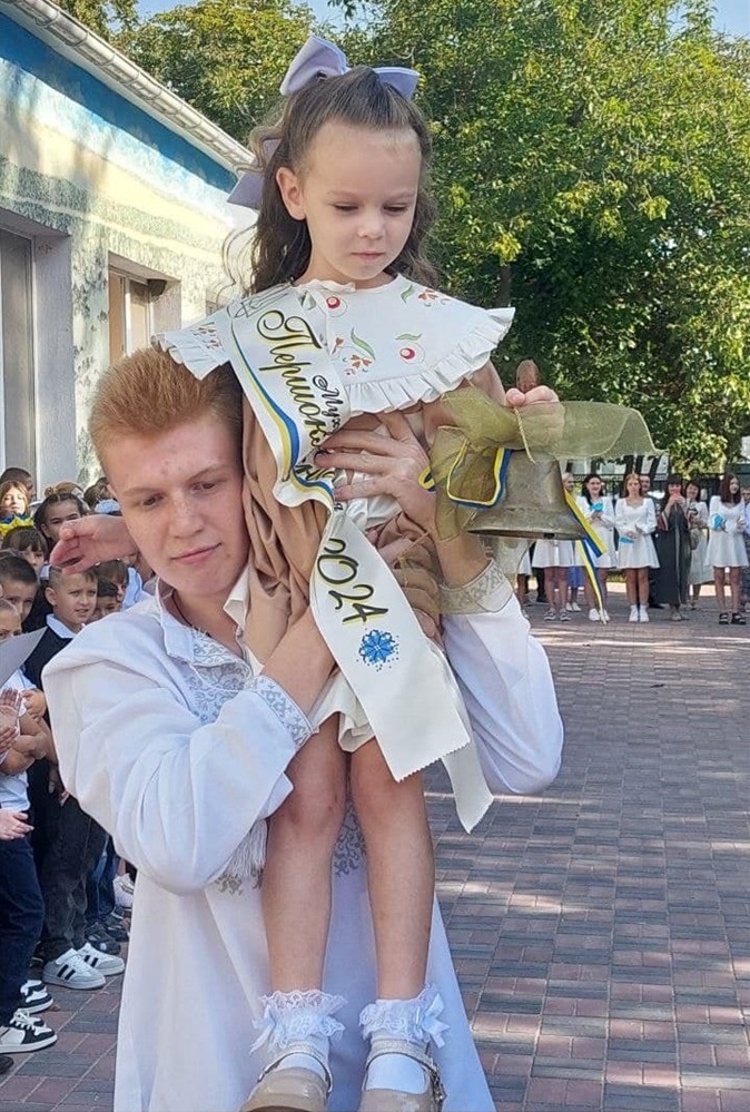 Першокласниця та одинадцятикласник подають Перший дзвоник