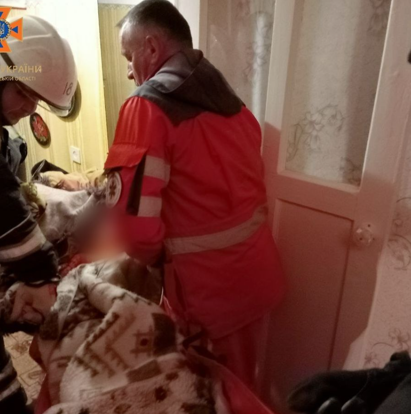 Рятівники допомагають перенести хвору жінку до швидкої