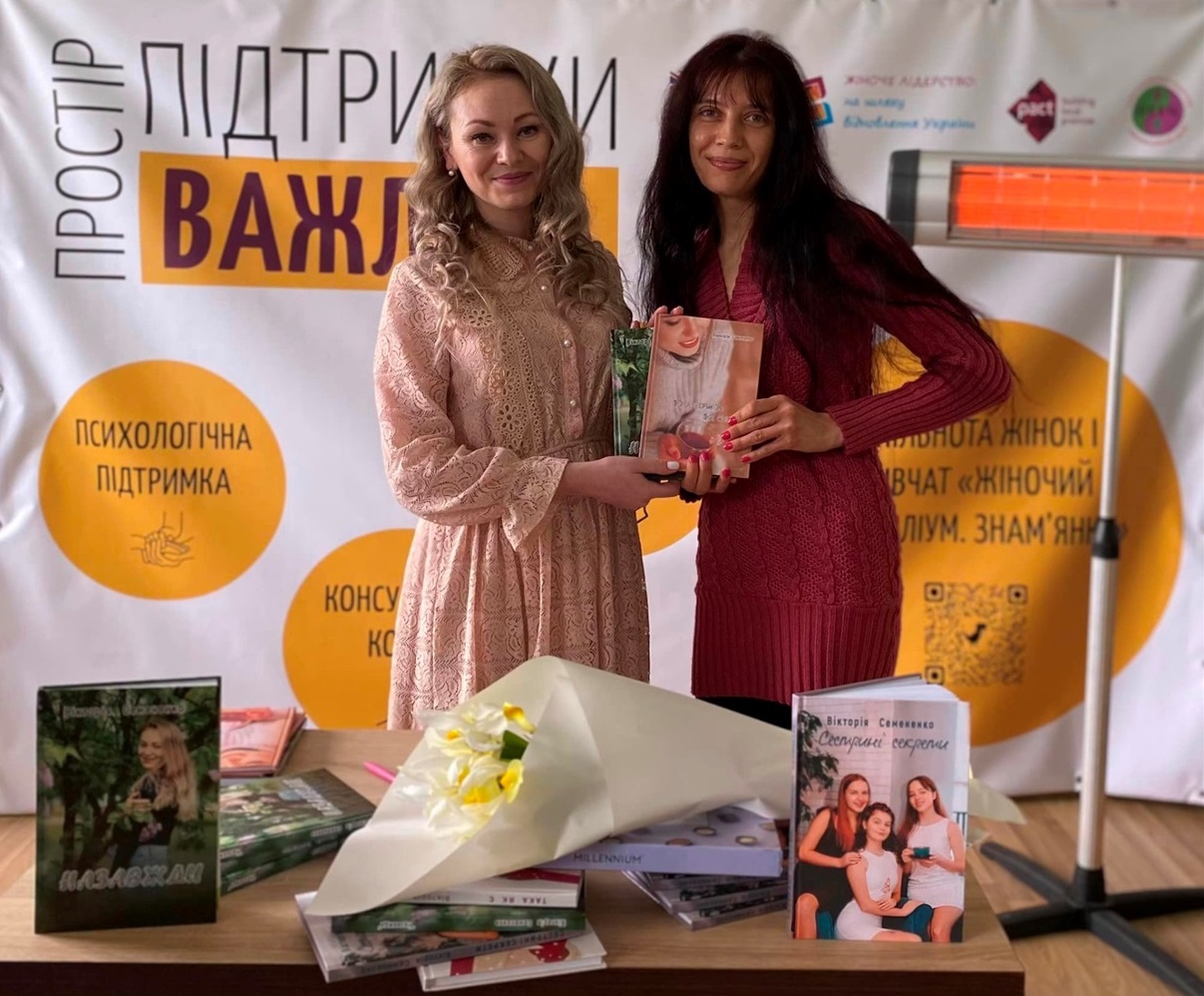Вікторія Семененко дає книгу з автографом одній із учасниць заходу