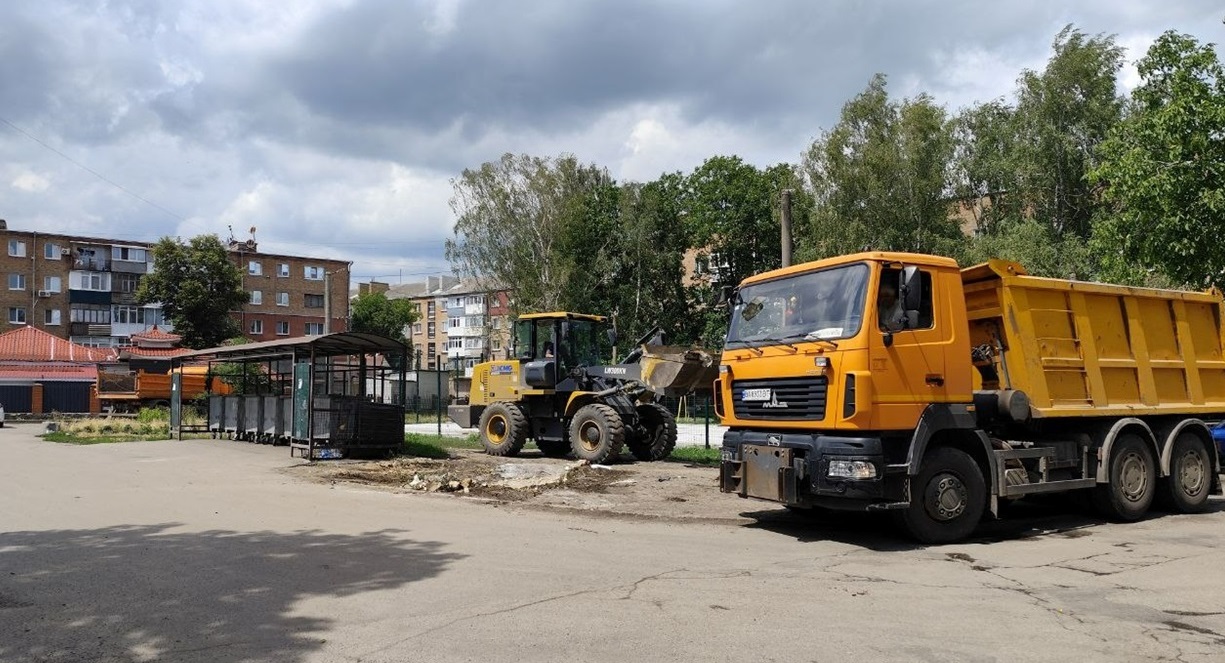 Працівники комунального підприємства прибирають сміття біля сміттєвого майданчика