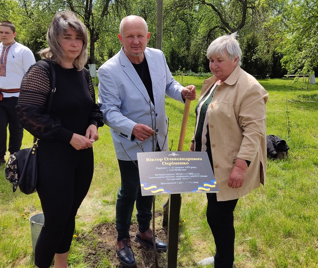 Дружина Олена  та мама Олена загиблого Віктора Охріменка разом з Олександрома Іськовим саджають деревце.