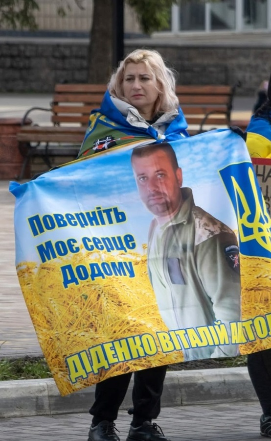 Мама Віталія Діденка - Ірина, тримає прапор зі світлиною сина