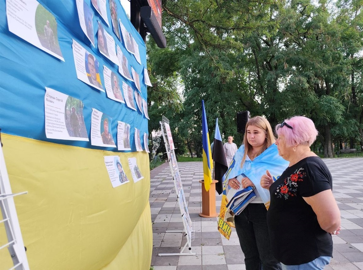 Голова громади Наталія Стиркуль та дружина зниклого безвісти захисника біля світлин