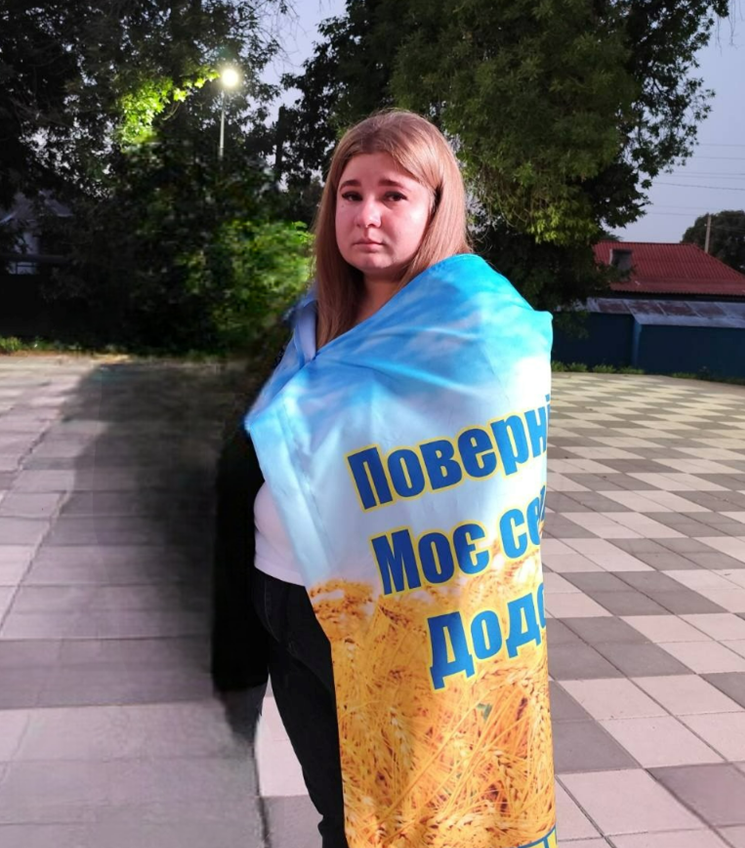 Альона Діденко загорнута в прапор на якому надпис: "Поверніть моє серце додому"